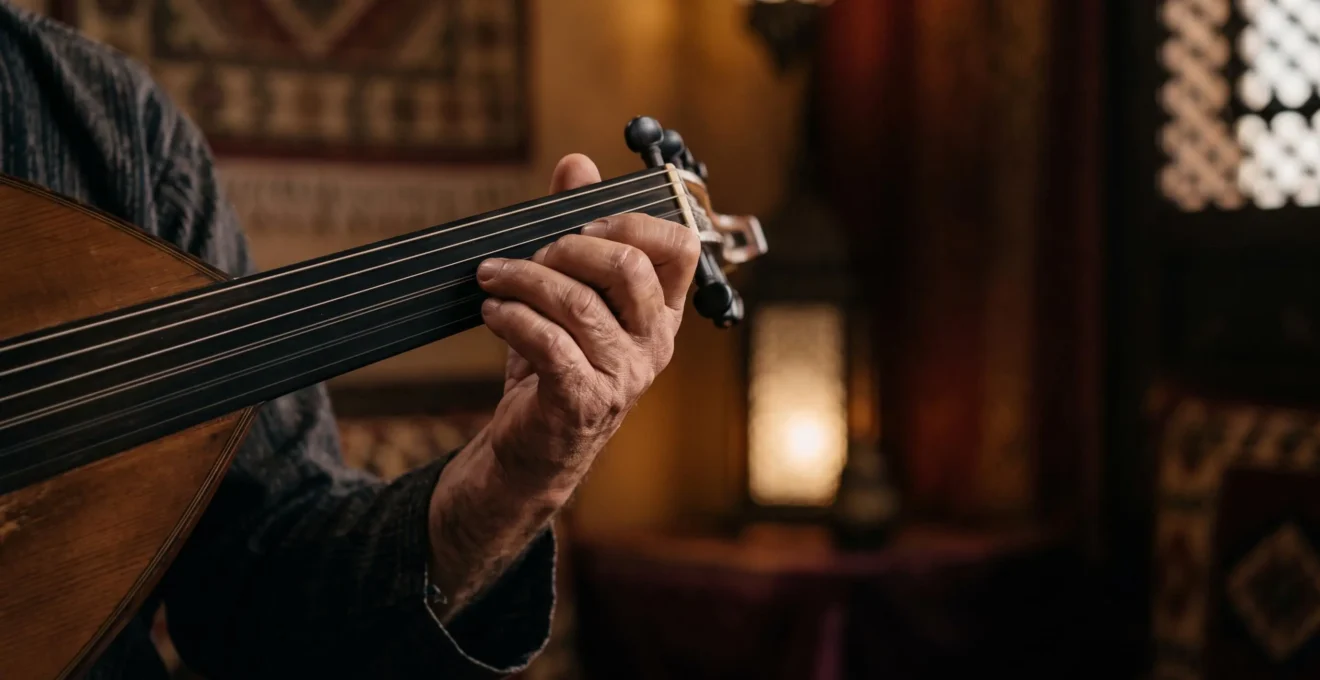 Close-up of a musician's hand sliding along the fretless neck of an oud during a quarter-tone performance